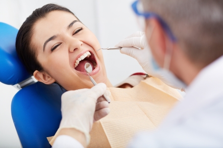 Close-up of girl with open mouth during oral checkup at the dentistsの写真素材