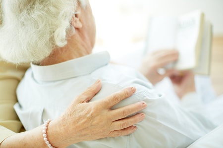 Close-up of senior female hand on her husband shoulder during readingの写真素材