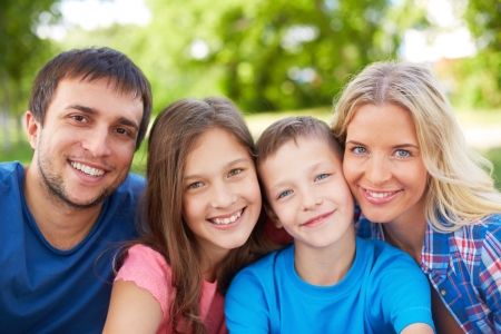 Photo of happy family of four looking at camera outdoorsの写真素材