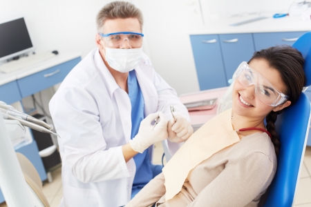 Happy girl in protective eyeglasses looking at camera with toothy smile at the dentistsの写真素材