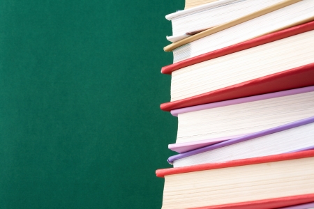 Colorful stack of textbooks on background of blackboardの写真素材