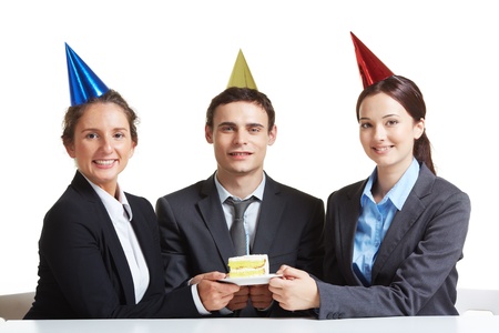 Portrait of young business partners in birthday caps holding piece of cake on saucer and looking at camera の写真素材