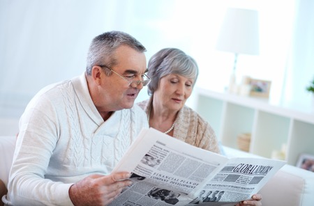Portrait of mature couple reading newspaper togetherの写真素材