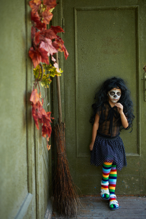 Portrait of Halloween girl with broom on background of wall of dilapidated houseの写真素材