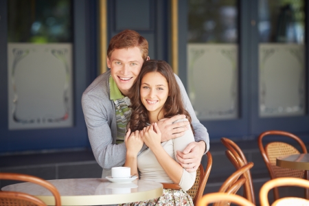 Happy guy embracing his girlfriend in cafe on summer dayの写真素材