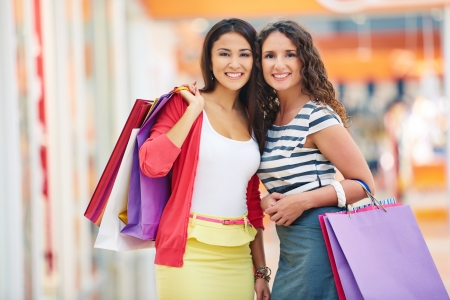 Gorgeous girlfriends with paperbags looking at camera in trade centerの写真素材
