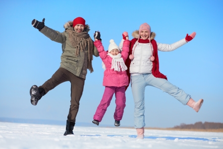 Happy parents and their daughter having fun in winterの写真素材