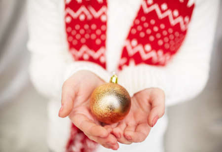 Image of decorative golden toy ball on female hands