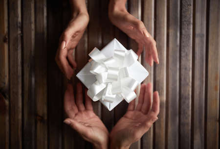 Image of female hands giving Christmas present to her friendの写真素材