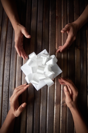 Image of two pairs of female hands by Christmas present in giftboxの写真素材