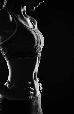 Body of slim female in activewear standing in isolation