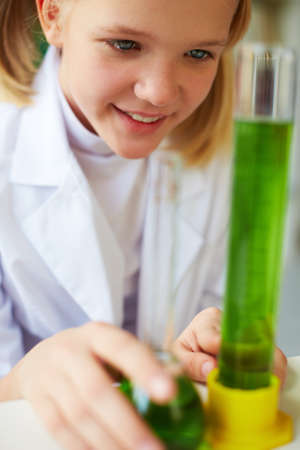 Portrait of cute schoolgirl studying chemical liquid in laboratory