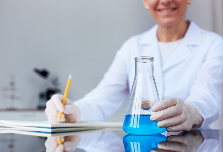 Image of glass flask with blue liquid held by chemist in laboratoryの写真素材