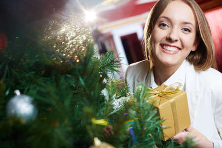 Portrait of joyful female with xmas present looking at camera with smileの写真素材