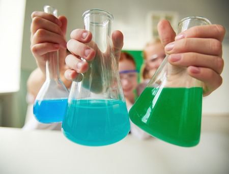 Three tubes with chemical liquids held by schoolchildren
