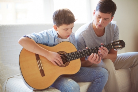 Portrait of handsome young man teaching his son how to play the guitarの写真素材