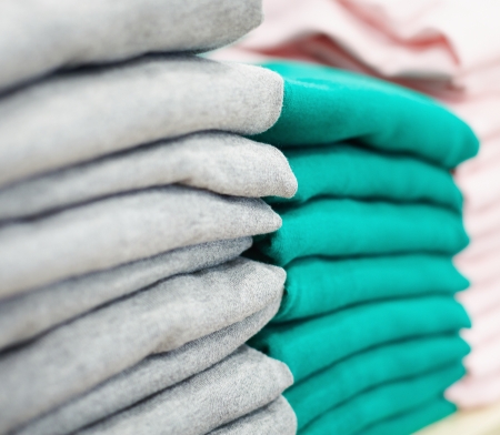Stack of new green and grey pullovers in clothing departmentの写真素材