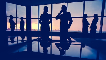 Silhouettes of several colleagues communicating in officeの写真素材