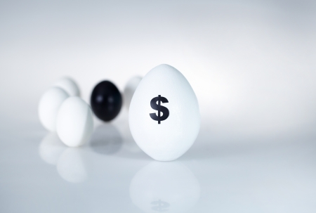 Image of big white egg with dollar sign on background of small eggsの写真素材