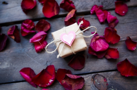 Image of valentine giftbox with small pink heart surrounded by rose petalsの写真素材