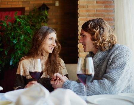 Portrait of amorous young couple drinking red wine in restaurantの写真素材