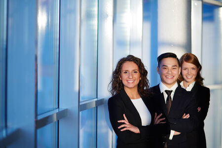 Three successful business partners looking at camera with smilesの写真素材