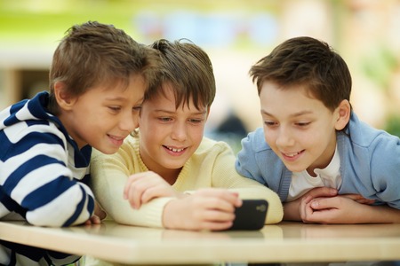 Three boys surfing the net on smartphoneの写真素材