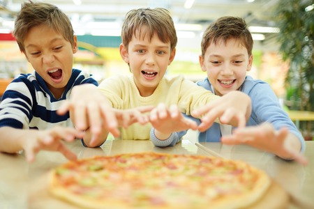 Three funny boys eating pizza in cafe の写真素材