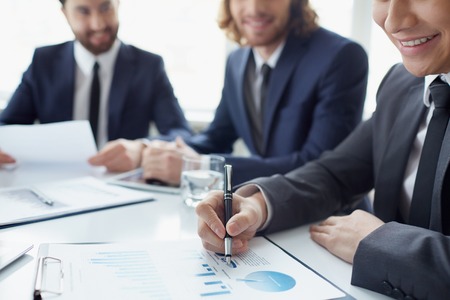Three men discussing spreadsheet with charts