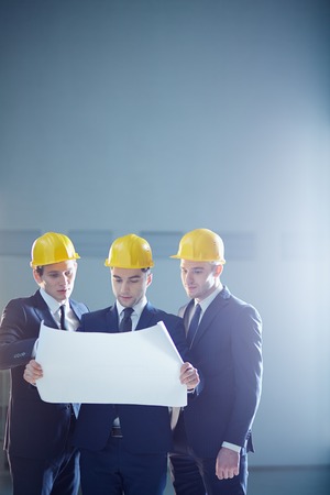 Copy-spaced image of a three construction workers holding a draft and discussing something の写真素材