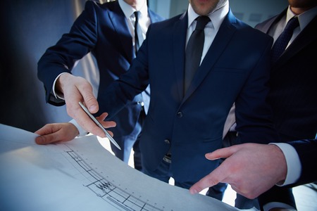 Cropped image of professional engineers working with the construction blue print on the foreground の写真素材