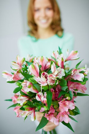 Close-up of bunch of pink lilies held by femaleの写真素材