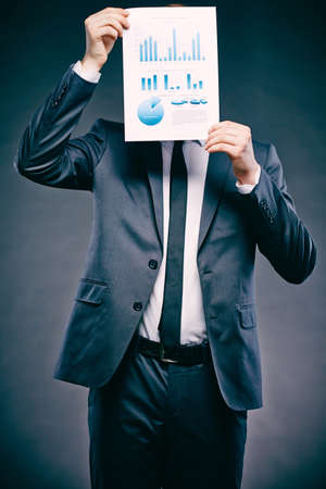 Portrait of a young businessman holding document in front of his face の写真素材