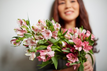 Close-up of bunch of pink lilies held by femaleの写真素材