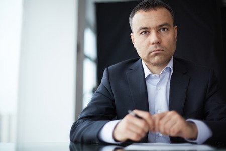 Serious businessman looking at camera at workplaceの写真素材