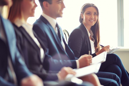 Row of business people sitting at seminar, focus on attentive young female