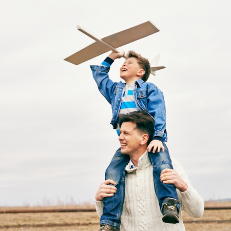 Photo of happy boy with toy airplane and his father playing together outsideの写真素材