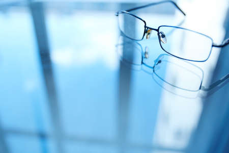Image of eyeglasses on workplace and its reflectionの写真素材