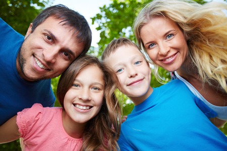 Photo of happy family of four looking at camera outdoorsの写真素材