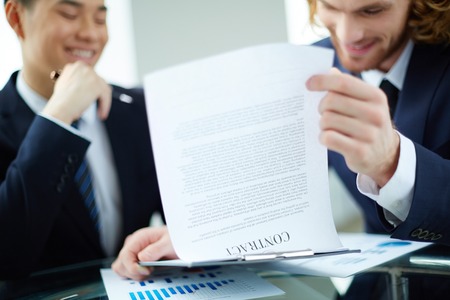 Two successful entrepreneurs reading and discussing business contractの写真素材