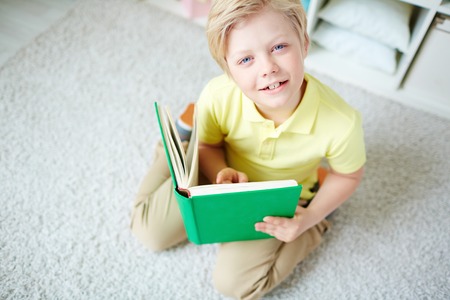 Portrait of clever boy reading book at homeの写真素材