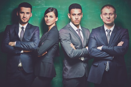 Group of elegant business partners looking at camera on green background