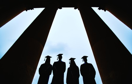 Outlines of four graduates between columns of university buildingの写真素材