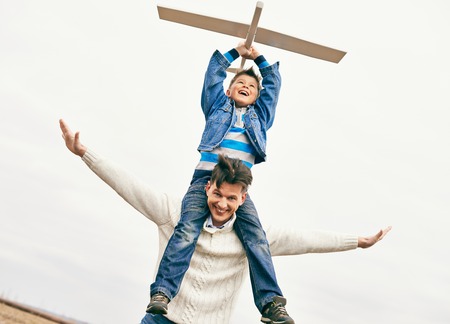 Photo of happy boy with toy airplane and his father against skyの写真素材