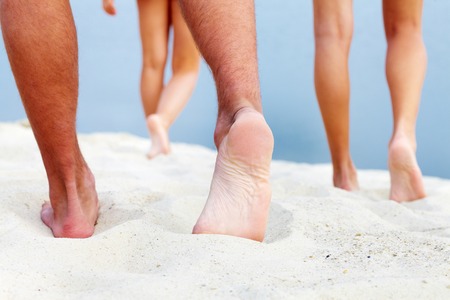 Soles of teenagers walking down sandy beachの写真素材