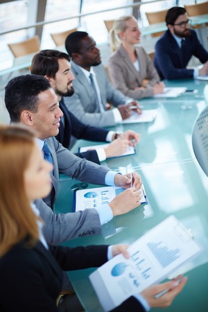 Row of business people listening to presentation at seminar with focus on elegant young man