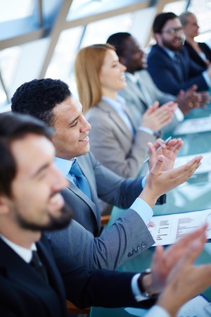 Young business partners applauding to reporter after listening to presentation at seminar