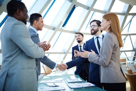 Group of business people congratulating their colleagues with striking grand dealの写真素材