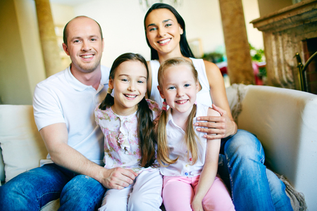 A young friendly family of four looking at camera at homeの写真素材