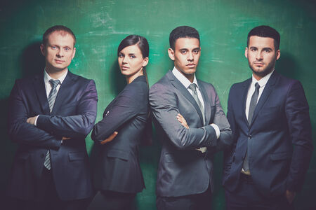 Group of elegant business partners looking at camera on green backgroundの写真素材